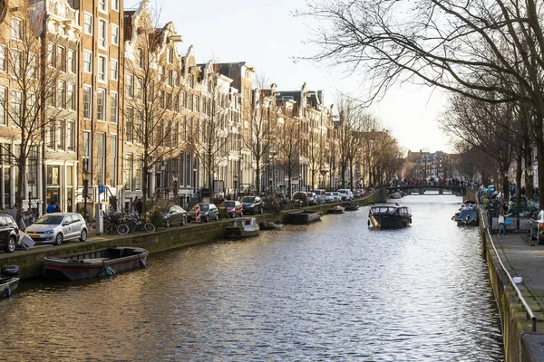 AMSTERDAM, PAÍSES BAJOS 28 DE MARZO DE 2016. Típica vista urbana en la tarde de primavera. El canal y los edificios de la construcción XVII-XVIII sobre terraplenes. El barco a pie flota en el canal —  Fotos de Stock