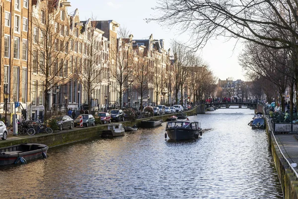 AMSTERDAM, PAÍSES BAJOS 28 DE MARZO DE 2016. Típica vista urbana en la tarde de primavera. El canal y los edificios de la construcción XVII-XVIII sobre terraplenes. El barco a pie flota en el canal — Foto de Stock