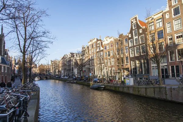 AMSTERDAM, NETHERLANDS on MARCH 28, 2016. Typical urban view in the spring afternoon. The channel and buildings of the XVII-XVIII construction on embankments. The walking ship floats on the channel — Stock Photo, Image