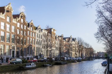 AMSTERDAM, NETHERLANDS on MARCH 28, 2016. Typical urban view in the spring afternoon. The channel and buildings of the XVII-XVIII construction on embankments.  clipart