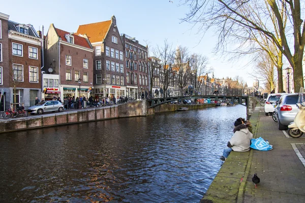 Amsterdam, Nizozemsko na 28 březnu 2016. Typický městský pohled v jarní večer. Most přes kanál a budovy stavby Xvii a Xviii na nábřežích — Stock fotografie