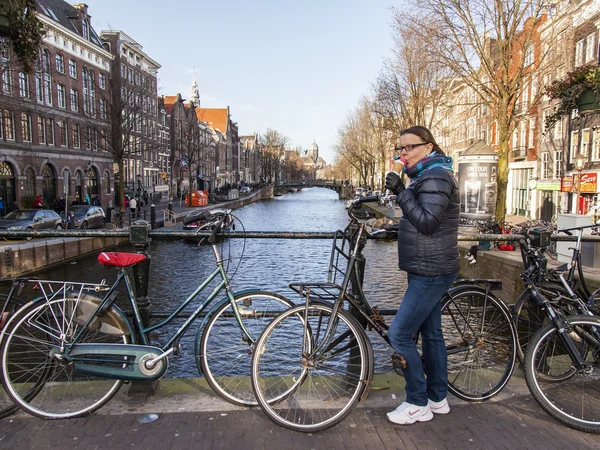 AMSTERDAM, NETHERLANDS on MARCH 27, 2016. City landscape. The woman with ice cream on the bridge against the city — Stock Photo, Image