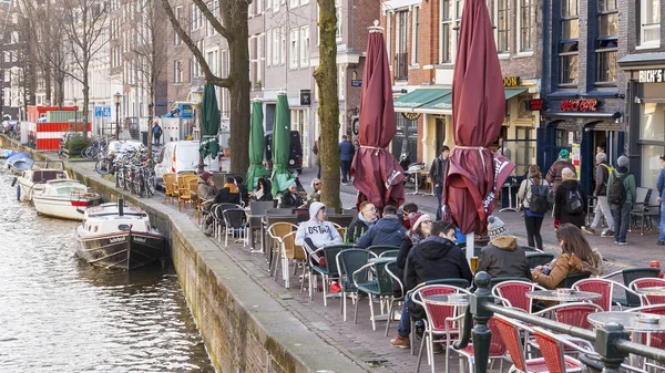 AMSTERDAM, NETHERLANDS on MARCH 28, 2016. Typical urban view in the spring. Little tables of summer cafe under the open sky. — Stock Photo, Image