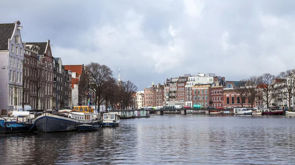 AMSTERDAM, NETHERLANDS on MARCH 28, 2016. River Amstel. Architectural complex of the embankment. Boats are moored at the coast. — Stock Photo, Image