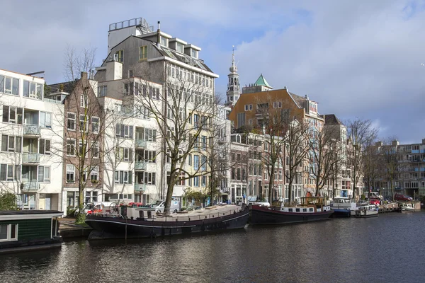 Amsterdam, Nederland op 27 maart 2016. Typisch stedelijke weergave in de lente-avond. Gebouwen van de bouw van de Xvii-Xviii van taluds en woonboten in de buurt van bank — Stockfoto