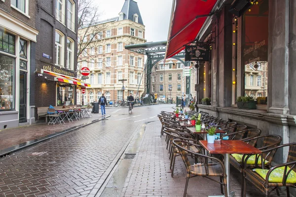 AMSTERDAM, PAÍSES BAJOS 28 DE MARZO DE 2016. Típica vista urbana en la noche de primavera. Pequeñas mesas de café de verano en la acera . — Foto de Stock