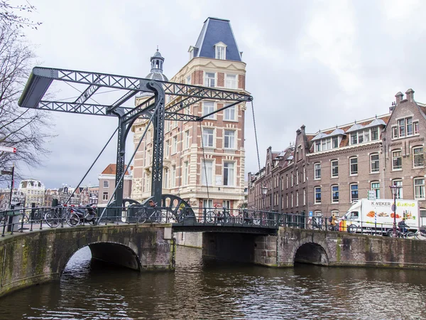 AMSTERDAM, NETHERLANDS on MARCH 28, 2016. Typical urban view in the spring morning. An old movable bridge via the channel — Stock Photo, Image