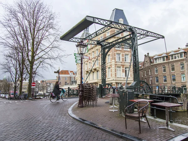 AMSTERDAM, NETHERLANDS on MARCH 28, 2016. Typical urban view in the spring morning. An old movable bridge via the channel — Stock Photo, Image