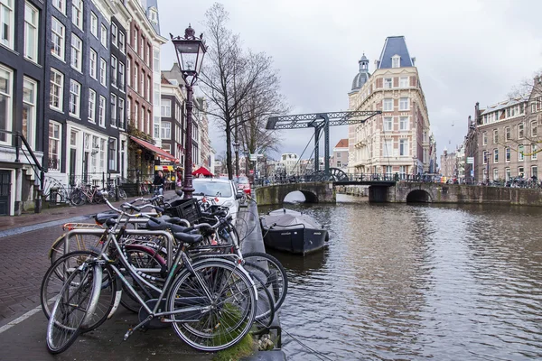 AMSTERDAM, NETHERLANDS on MARCH 28, 2016. Typical urban view in the spring morning. An old movable bridge via the channel in the distance — Stock Photo, Image