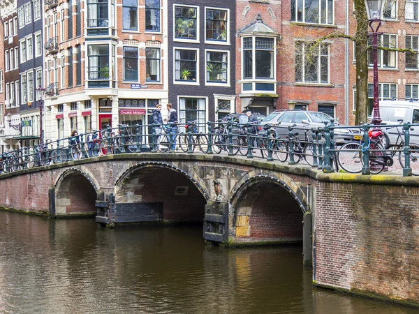 AMSTERDAM, PAÍSES BAJOS 29 DE MARZO DE 2016. Típica vista urbana en la tarde de primavera. Las bicicletas están estacionadas en la caseta a través del canal — Foto de Stock