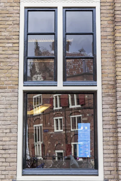 AMSTERDAM, PAÍSES BAJOS 29 DE MARZO DE 2016. Típica vista urbana en la tarde de primavera. Edificios antiguos se reflejan en una ventana —  Fotos de Stock