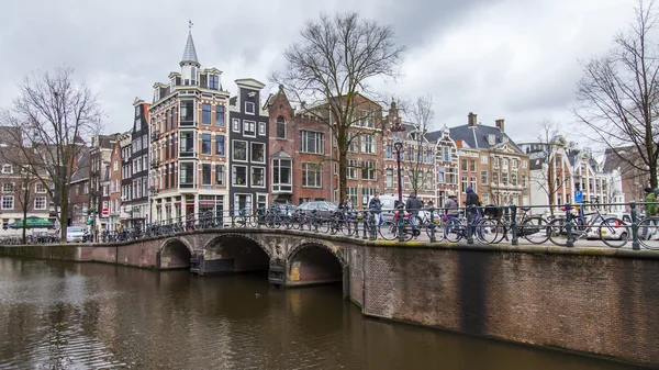 Amsterdam, Nederland op 27 maart 2016. Typisch stedelijke weergave in de lente-avond. De brug door middel van het kanaal en de gebouwen van de bouw van de Xvii-Xviii op taluds — Stockfoto