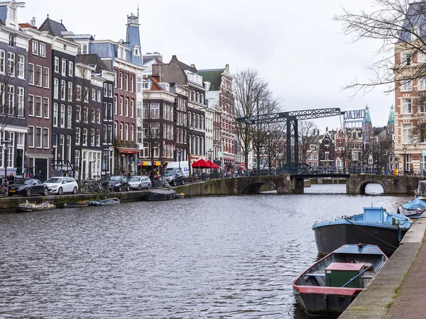 Amsterdam, Nederland op 27 maart 2016. Typisch stedelijke weergave in de lente-avond. De brug door middel van het kanaal en de gebouwen van de bouw van de Xvii-Xviii op taluds — Stockfoto