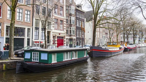 AMSTERDAM, NETHERLANDS on MARCH 27, 2016. Typical urban view. Houseboats near the bank — Stock Photo, Image