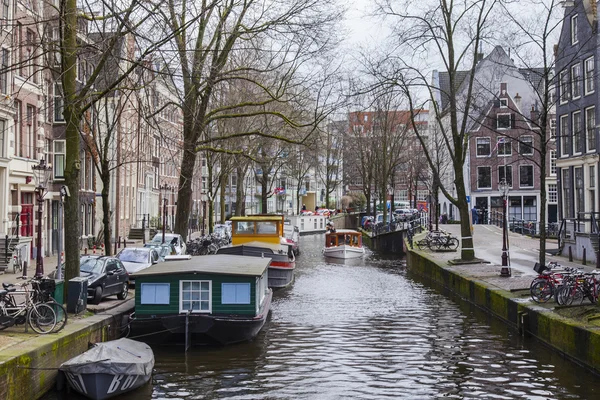 AMSTERDAM, NETHERLANDS on MARCH 27, 2016. Typical urban view. Houseboats near the bank — Stock Photo, Image