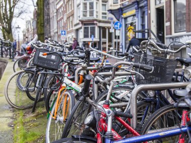 Amsterdam, Hollanda 30 Mart 2016 tarihinde. Kentsel görünüm. Bisikletler kanal setine park edilmiş.