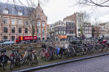 Amsterdam, Hollanda 30 Mart 2016 tarihinde. Kentsel görünüm. Bisikletler kanal setine park edilmiş.