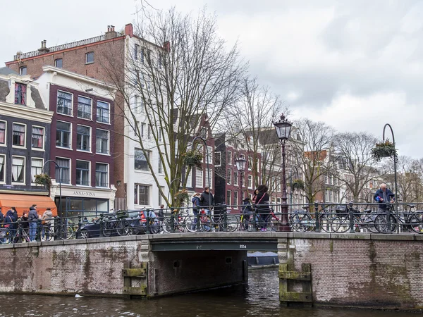 AMSTERDAM, PAÍSES BAJOS el 27 de marzo de 2016. Típica vista urbana en la noche de primavera. El puente a través del canal y los edificios de la construcción XVII-XVIII sobre terraplenes — Foto de Stock