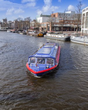 Amsterdam, Hollanda üzerinde 27 Mart 2016. Amstel Nehri yürüyüş gemi yüzer tipik kentsel görünümü