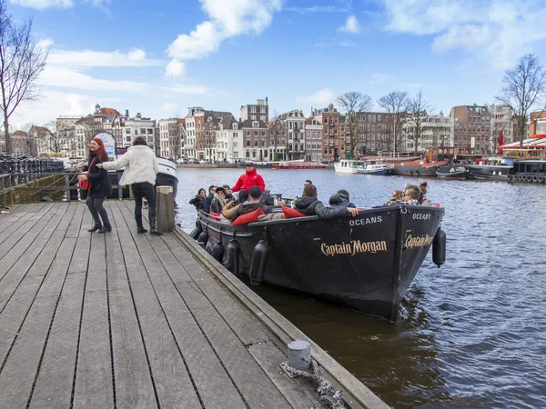 AMSTERDAM, PAÍSES BAJOS el 27 de marzo de 2016. Típica vista urbana. El barco a pie con gente y bar está a bordo amarrado a la orilla del río Amstel — Foto de Stock