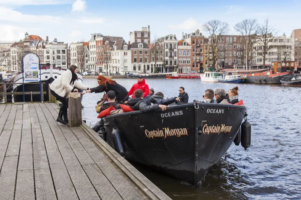 AMSTERDAM, NETHERLANDS on MARCH 27, 2016. Typical urban view. The walking ship with people and bar is onboard moored to the river bank Amstel — Stock Photo, Image