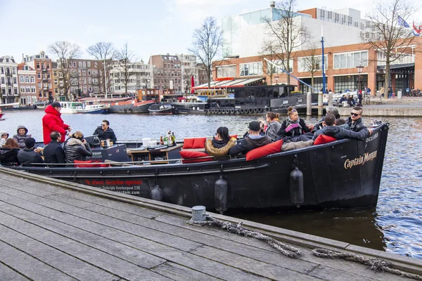 AMSTERDAM, PAÍSES BAJOS el 27 de marzo de 2016. Típica vista urbana. El barco a pie con gente y bar está a bordo amarrado a la orilla del río Amstel — Foto de Stock