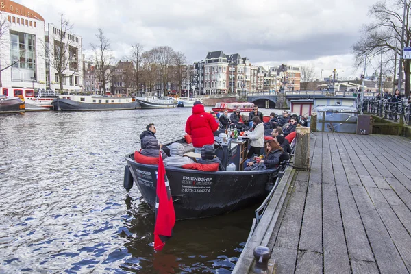 AMSTERDAM, PAÍSES BAJOS el 27 de marzo de 2016. Típica vista urbana. El barco a pie con gente y bar está a bordo amarrado a la orilla del río Amstel — Foto de Stock
