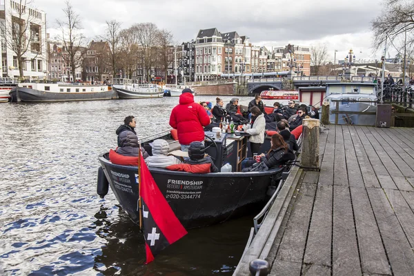 AMSTERDAM, NETHERLANDS on MARCH 27, 2016. Typical urban view. The walking ship with people and bar is onboard moored to the river bank Amstel — Stock Photo, Image