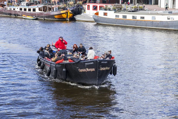 Amsterdam, Nizozemsko na 27 březen 2016. Typický městský pohled. Walking loď s lidmi a bar je na palubě plave po proudu řeky Amstel — Stock fotografie