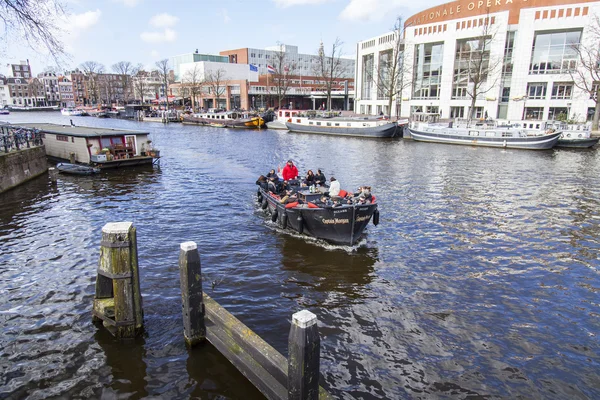 AMSTERDAM, NETHERLANDS on MARCH 27, 2016. The typical urban view. the Walking ship with people and bar is onboard floats down the river Amstel — Stock Photo, Image