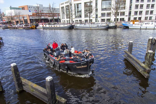 AMSTERDAM, NETHERLANDS on MARCH 27, 2016. The typical urban view. the Walking ship with people and bar is onboard floats down the river Amstel — Stock Photo, Image