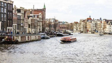 Amsterdam, Hollanda üzerinde 27 Mart 2016. Amstel Nehri yürüyüş gemi yüzer tipik kentsel görünümü