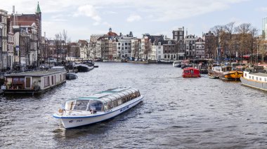 Amsterdam, Hollanda üzerinde 27 Mart 2016. Amstel Nehri yürüyüş gemi yüzer tipik kentsel görünümü