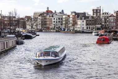 Amsterdam, Hollanda üzerinde 27 Mart 2016. Amstel Nehri yürüyüş gemi yüzer tipik kentsel görünümü