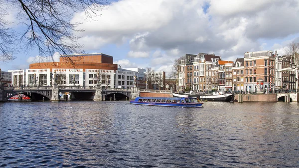 AMSTERDAM, NETHERLANDS on MARCH 29, 2016. Typical urban view in the spring afternoon. Amstel River Embankment. Opera theater. — Stock Photo, Image