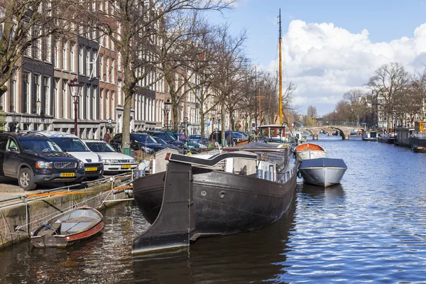 2016 年 3 月 27 日にアムステルダム、オランダ。典型的な都市景観です。銀行の近くのハウスボート — ストック写真