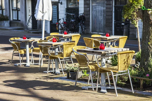 AMSTERDAM, PAÍSES BAJOS el 27 de marzo de 2016. Típica vista urbana en la mañana de primavera. Pequeñas mesas de café de verano bajo el cielo abierto —  Fotos de Stock