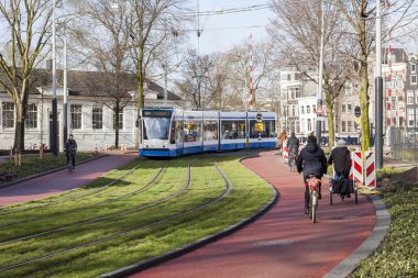 Amsterdam, Hollanda üzerinde 30 Mart 2016. Bahar öğleden sonra tipik kent görünümünde. Tramvay caddeden aşağı taşır