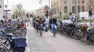 Amsterdam, Hollanda üzerinde 30 Mart 2016. Kentsel görünümü. Bisikletçiler caddeden aşağı git