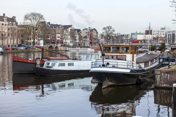 Amsterdam, Nizozemsko na 31 březnu 2016. Typický městský pohled na jaře. Kanál a budovy stavby Xvii a Xviii na náspy. Hausbóty u banky — Stock fotografie