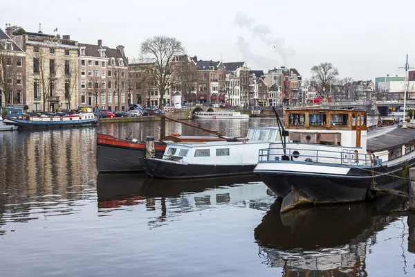 AMSTERDAM, NETHERLANDS on March 31, 2016. Типичный вид на город весной. Канал и здания XVII-XVIII вв. постройки на набережных. Катера у берега — стоковое фото