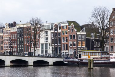 Amsterdam, Hollanda üzerinde 31 Mart 2016. Bahar tipik kent görünümünde. Amstel Nehri ve XVII-XVIII inşaat bentleri üzerinde binalar. Yüzen Banka Yakındaki
