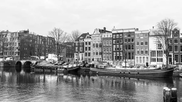 AMSTERDAM, PAESI BASSI il 31 marzo 2016. Tipica vista urbana in primavera. Il fiume Amstel e gli edifici della XVII-XVIII costruzione su argini. Houseboats vicino alla banca — Foto Stock