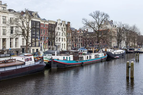AMSTERDAM, PAYS-BAS, le 31 mars 2016. Vue urbaine typique au printemps. La rivière Amstel et les bâtiments de la construction XVII-XVIII sur les remblais. Péniches près de la banque — Photo
