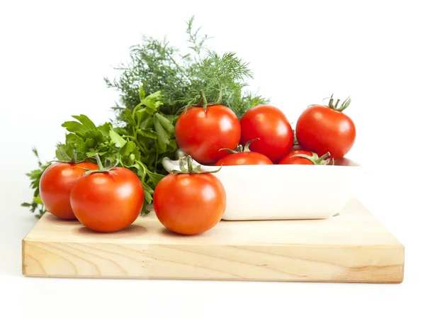 Fresh cherry tomatoes and bunch of greens on a kitchen table — Stock Photo, Image