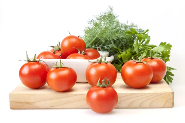 Tomates de cereja frescos e ramo de verdes em uma mesa de cozinha — Fotografia de Stock