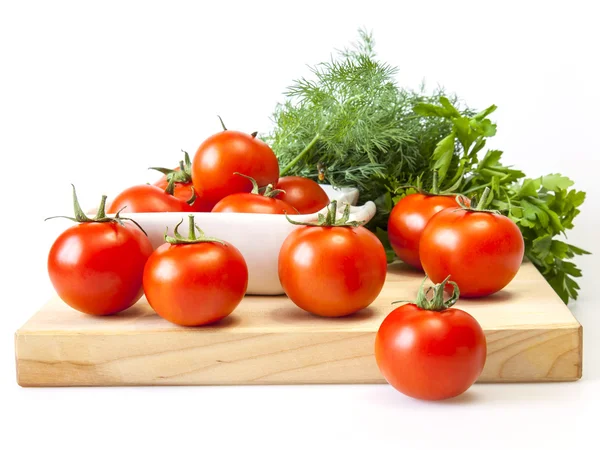 Fresh cherry tomatoes and bunch of greens on a kitchen table — Stock Photo, Image