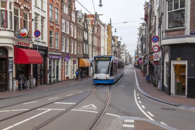 Amsterdam, Hollanda üzerinde 31 Mart 2016. Bahar öğleden sonra tipik kent görünümünde. Tramvay caddeden aşağı taşır