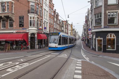 Amsterdam, Hollanda üzerinde 31 Mart 2016. Bahar öğleden sonra tipik kent görünümünde. Tramvay caddeden aşağı taşır