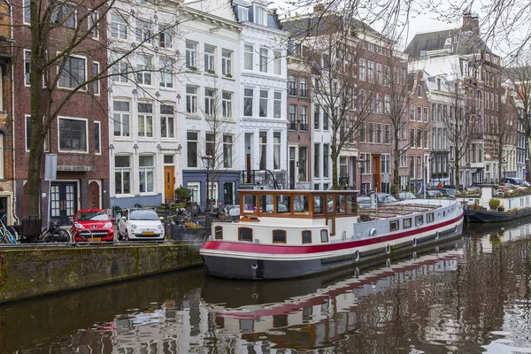 AMSTERDAM, PAÍSES BAJOS 31 DE MARZO DE 2016. Típica vista urbana. Edificios de la construcción XVII-XVIII sobre terraplenes. Casas flotantes cerca de las orillas — Foto de Stock